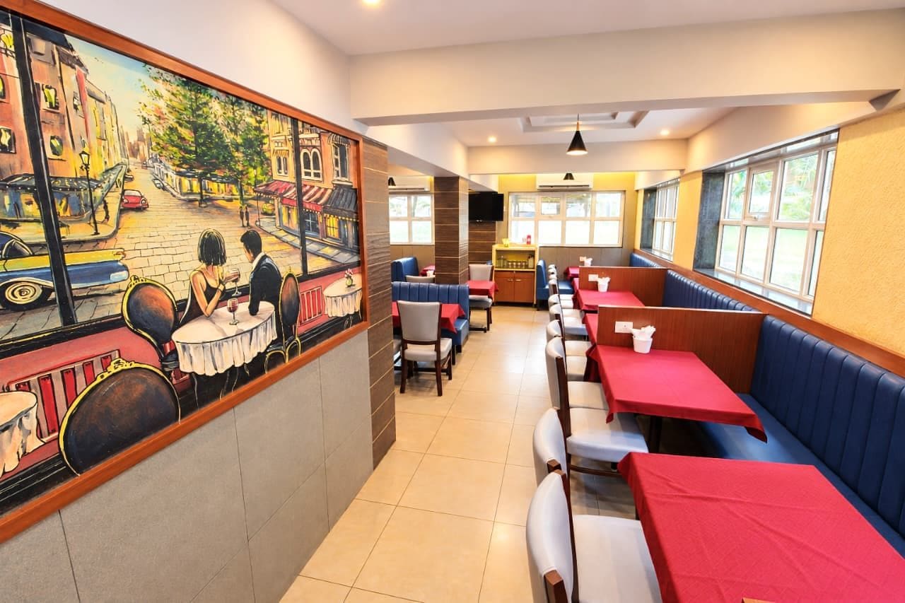 Ein Restaurant mit Sitzecken und Tischen, einer Wandmalerei und einem Fernsehbildschirm.