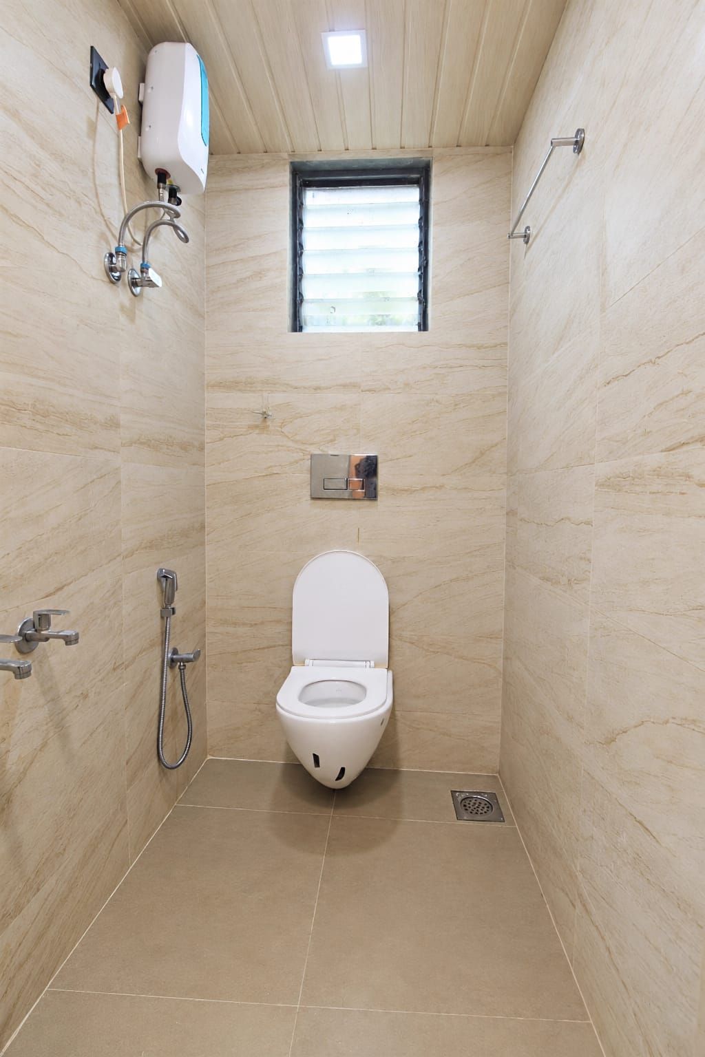 A small, tiled bathroom with a toilet, a shower, and a window.