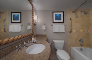 Un bagno con lavandino, WC, vasca e due quadri appesi al muro.