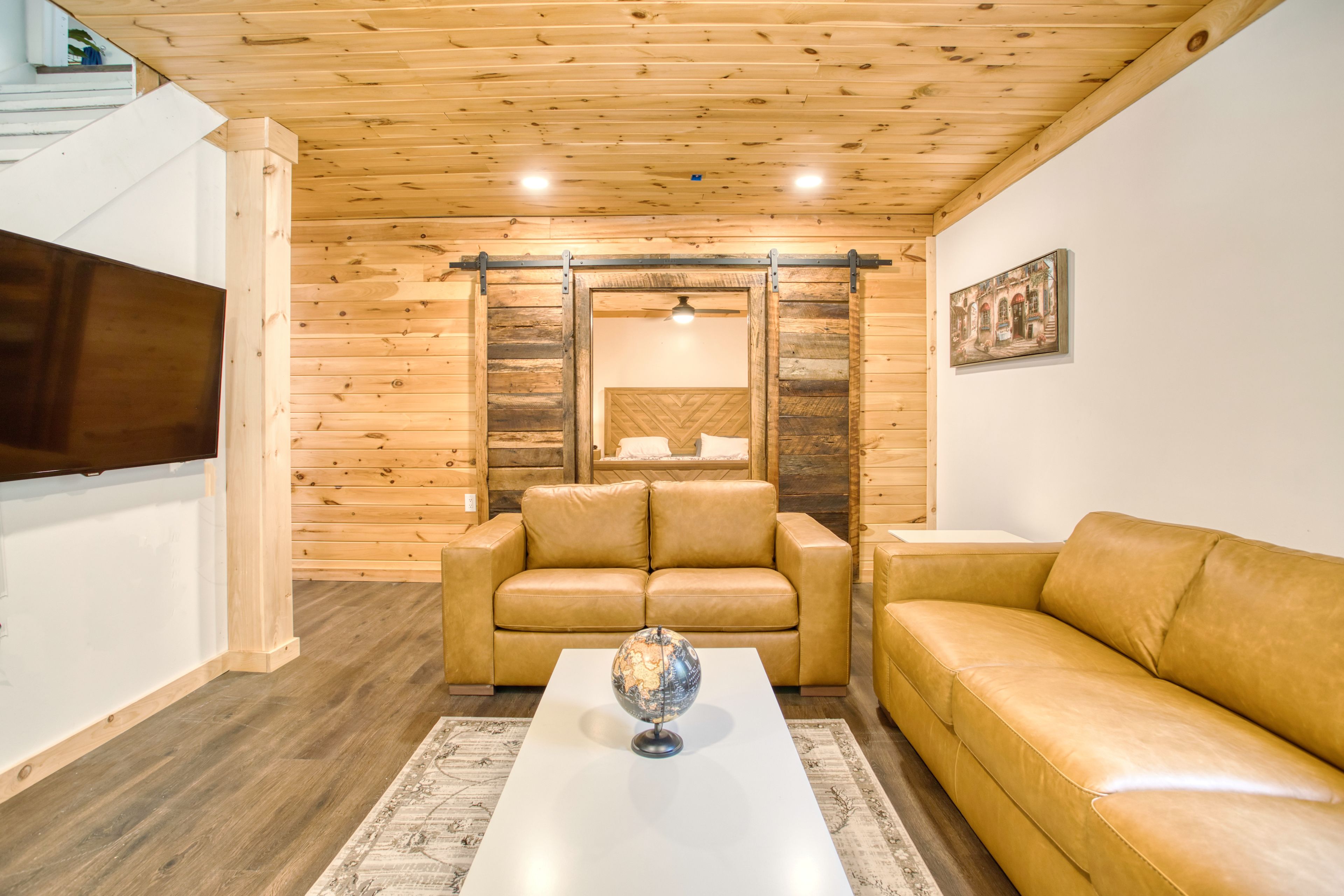 A living room with wooden walls, a sofa, a coffee table, and a television.
