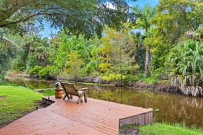 A wooden dock extending over a calm body of water, surrounded by lush greenery and trees. - Golden Oaks Estate: Lagoon Pool, Treehouse, Private Lake & Acres of Waterfront Nature (Naples)