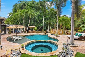 A swimming pool with a hot tub, surrounded by palm trees and a patio area with outdoor furniture. - Golden Oaks Estate: Lagoon Pool, Treehouse, Private Lake & Acres of Waterfront Nature (Naples)