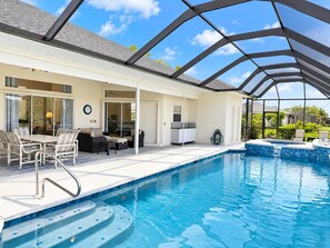 A covered outdoor swimming pool with a patio area, including a table and chairs, and a hot tub. - Rotonda Golf Course Villa with Pool & Hot Tub (Rotonda West)