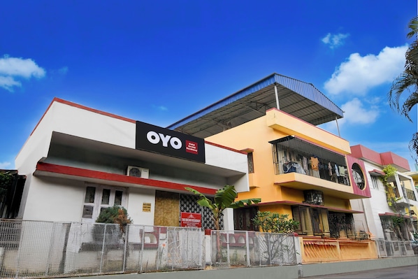 Um hotel chamado 'OYO' com uma placa indicando ser um hotel e residência de orquídeas.