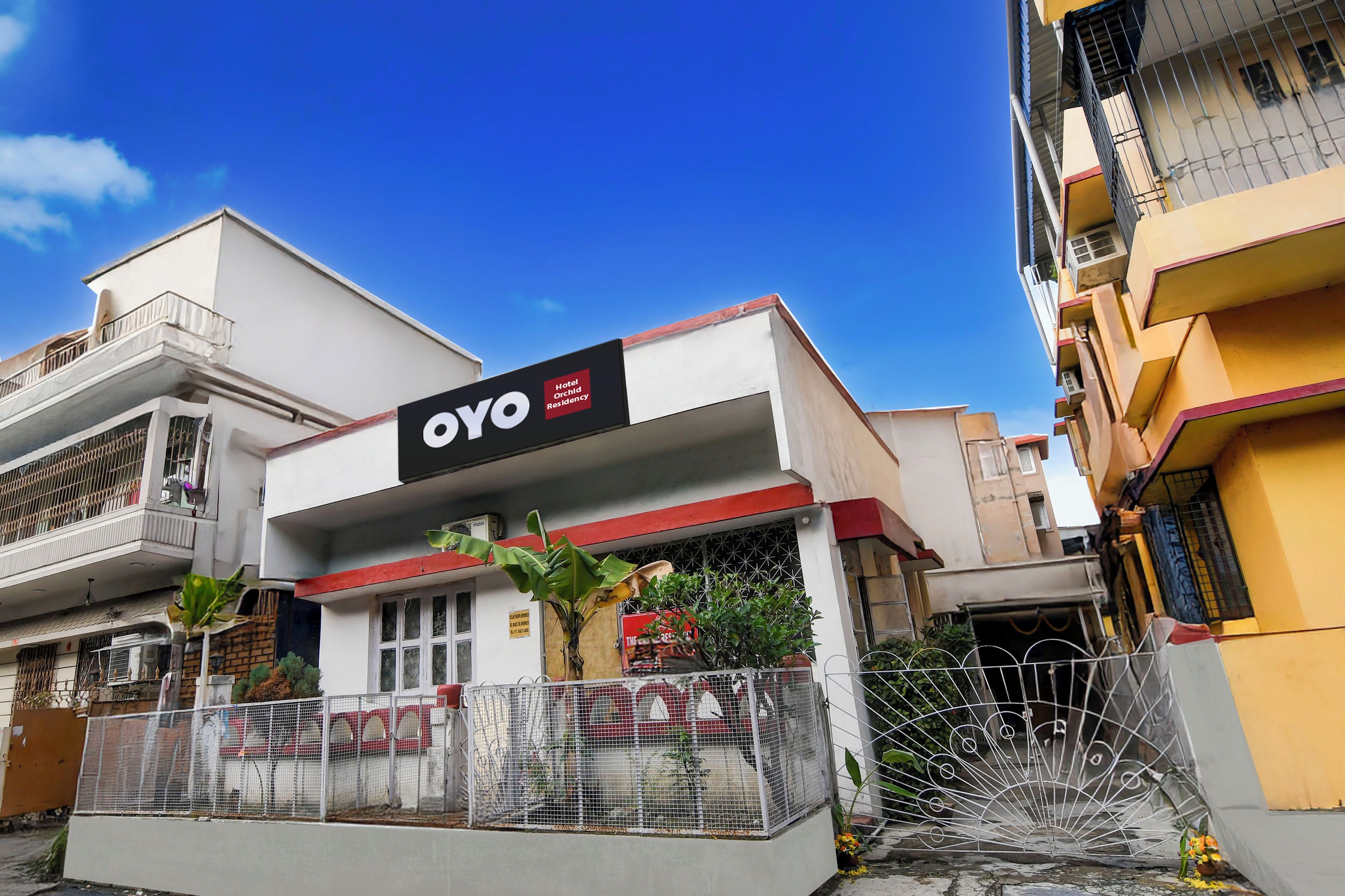 Ett hotell som heter OYO, med en skylt, en grind vid ingången och en synlig balkong.