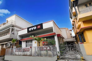 Un hotel llamado OYO con un letrero, una entrada con portón y un balcón visible.