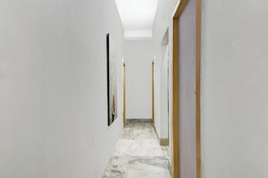 Un pasillo con paredes blancas, suelo de baldosas y puertas a la derecha.