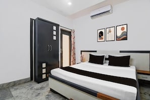 Quarto com cama, guarda-roupa, mesa de cabeceira e ar condicionado fixado na parede.
