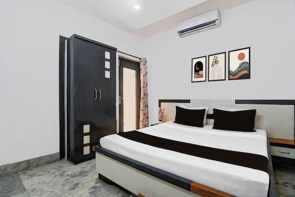 Un dormitorio con cama, armario, mesita de noche y aire acondicionado instalado en la pared.