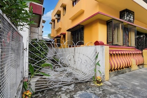 Un edificio residencial con entrada porticada, escaleras y un balcón con toldo a rayas.
