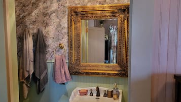 Um banheiro com pia branca, espelho com moldura elaborada e lustre.
