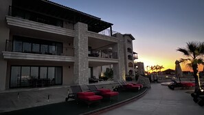 A hotel with multiple balconies, outdoor seating, and a view of the sunset.