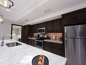 Una cocina moderna con gabinetes de madera oscura, electrodomésticos de acero inoxidable y encimera de mármol.