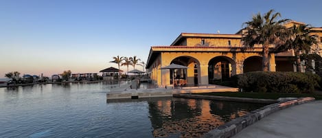 Un resort con piscina, zona de estar exterior y un edificio con arcos.