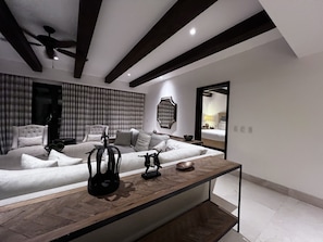 A modern bedroom with a large bed, a seating area, and a dining table.