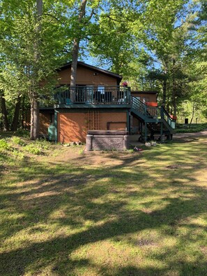 A two-story building with a balcony and a stone wall in front. - Private Georgian Bay Waterfront Cottage: Dock, Sand Beach, Hot Tub, Dogs OK (Tay)