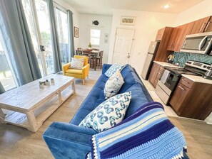 Ein Wohnzimmer mit einer Couch, einem Couchtisch und einer Küchenzeile mit Geräten.