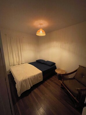 A small room with a bed, a chair, and a table. - Charming Lakeside Cottage (North Bay)