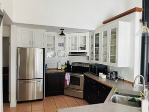 A kitchen with white cabinets, stainless steel appliances, and a black countertop. - Charming Lakeside Cottage (North Bay)