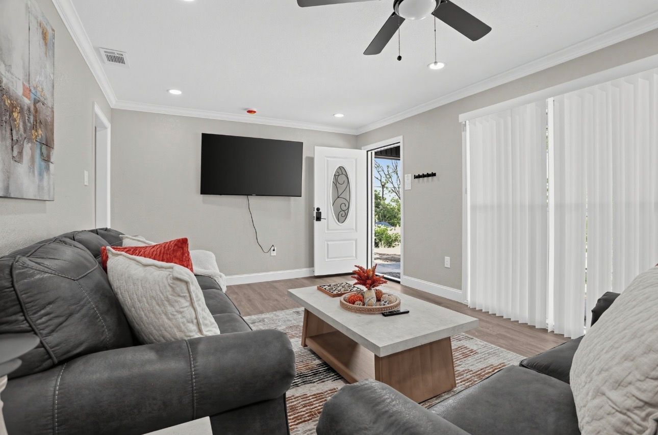 A living room with a sofa, coffee table, and a flat-screen TV mounted on the wall.