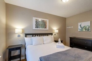 A hotel room with a bed, bedside tables, wall-mounted lamps, and artwork. - Modern Nashville Getaway (Nashville)
