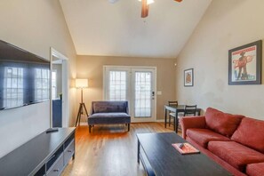 A living room with a sofa, a coffee table, a TV, and a dining area with chairs. - Modern Nashville Getaway (Nashville)