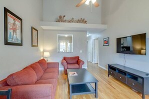 A living room with a sofa, a coffee table, a TV, and a ceiling fan. - Modern Nashville Getaway (Nashville)