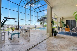 A spacious indoor area with a glass ceiling, a pool, and seating arrangements. - Riverfront 5BR Villa - Private Dock & Pool (Fort Myers)