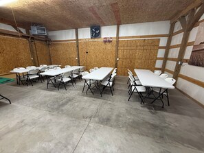 A conference room with white tables and chairs, wooden walls, and a ceiling fan. -  Shed in Great Bend perfect for your next fun gathering. (Great Bend)