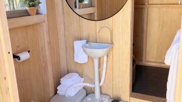 Une petite salle de bain en bois comprenant des toilettes, un lavabo et un espace douche.