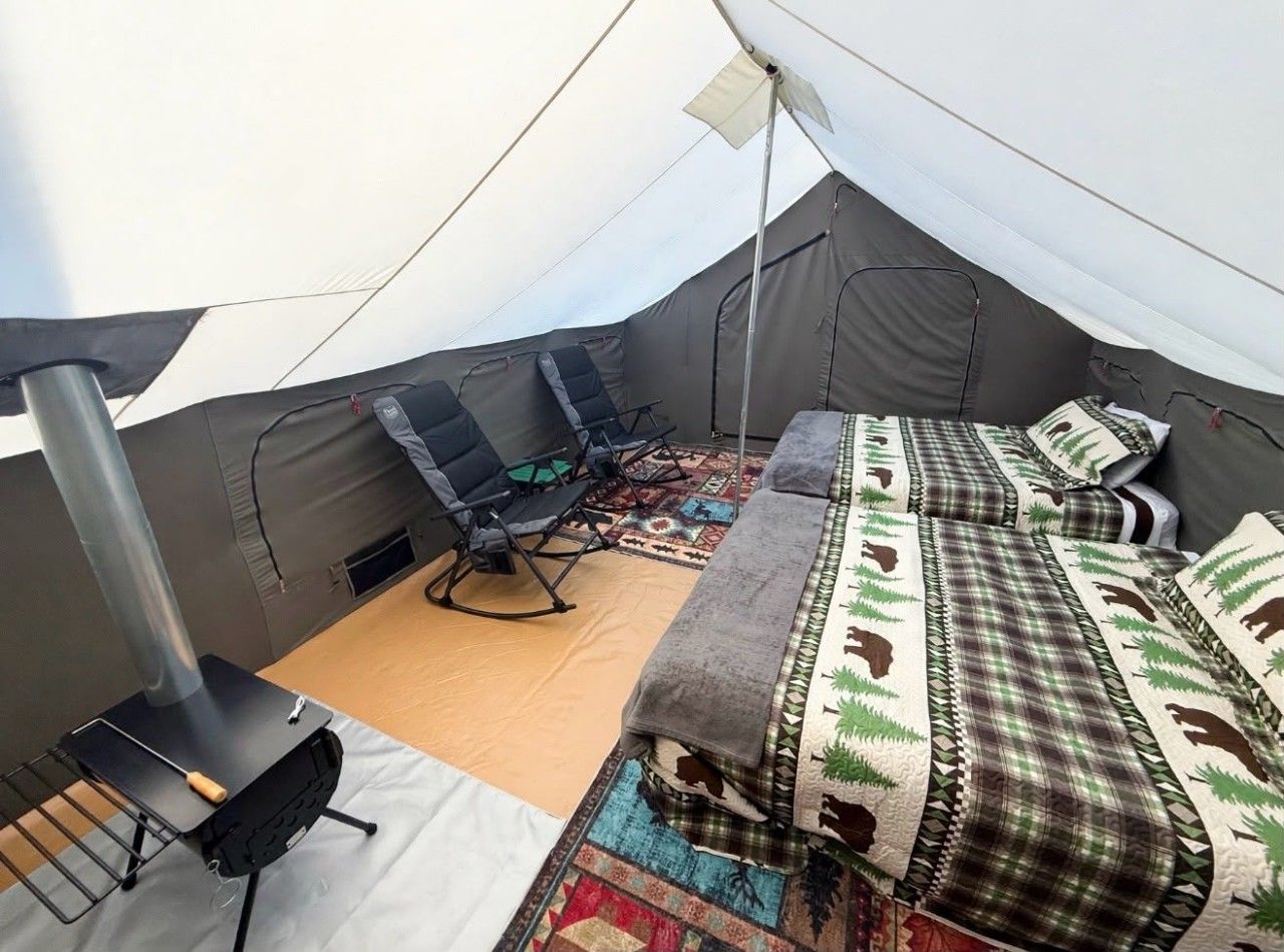 Une tente équipée d’un lit, d’une chaise et d’un réchaud portable.