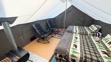 Ein Zelt mit Bett, Stuhl und einem Campingkocher.