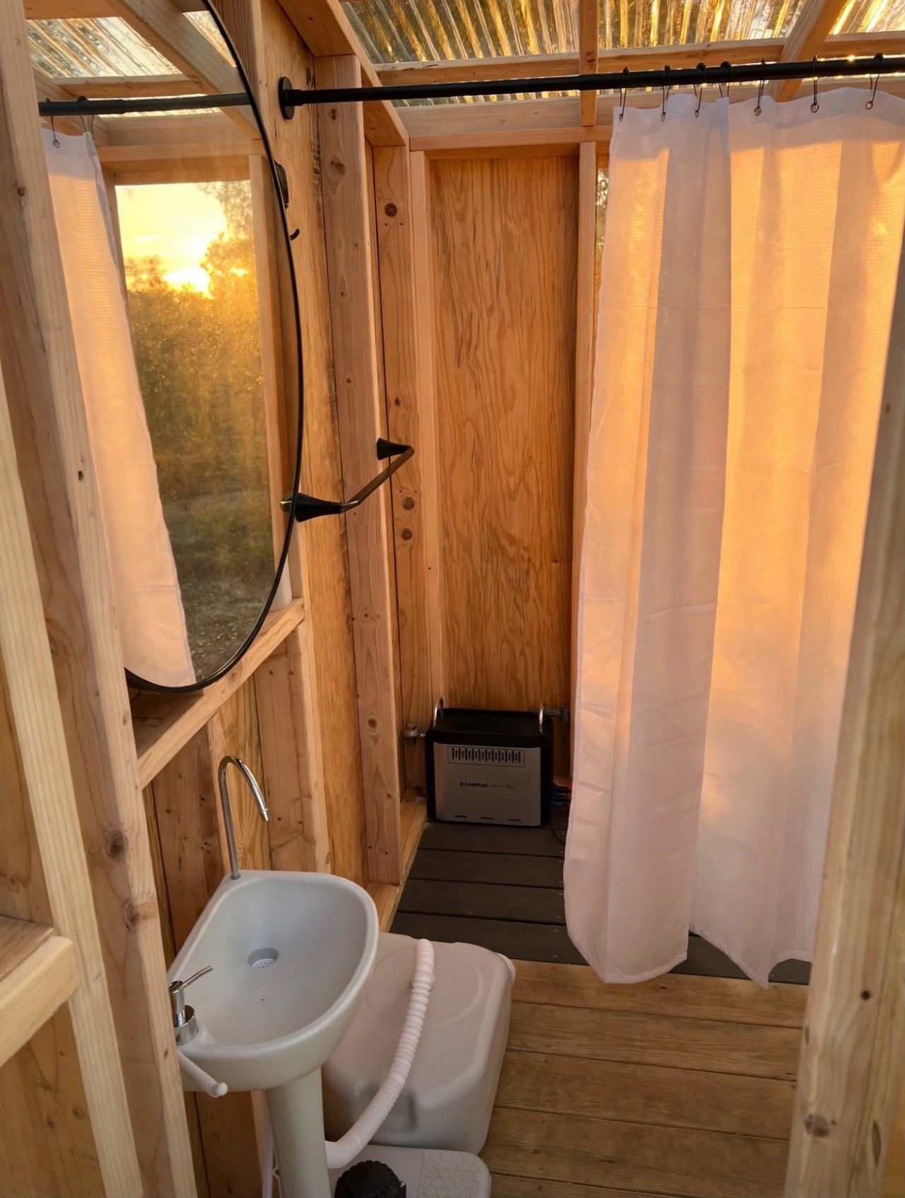 Een houten badkamer in een chalet, met een wastafel, toilet en douchegordijn.