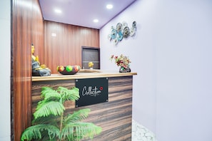 A reception desk with a sign that reads 'Collection,' a potted plant, and decorative items on the wall.