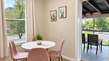 Un coin repas avec une table ronde, quatre chaises, une plante en pot et deux tableaux encadrés au mur.