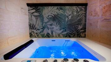 A hot tub with a control panel, surrounded by brick walls and a leaf-patterned backdrop.