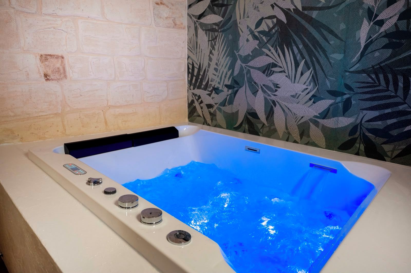 A hot tub with a control panel and a blue-lit water surface.