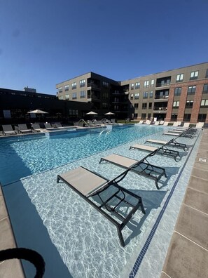 A swimming pool with lounge chairs and a building in the background. - Landing | Beautiful 1BD, Courtyard, Clubhouse (Fort Wayne)