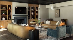 A modern living room with a sofa, armchairs, a coffee table, a fireplace, a TV, and a bookshelf. - Landing | Stylish 1BD in Lochridge (Cary)