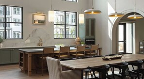 A modern kitchen with a large island, wooden chairs, pendant lighting, and a view of the outside. - Landing | Stylish 1BD in Lochridge (Cary)