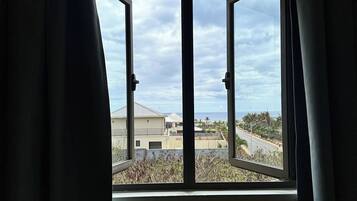A window with curtains, a view of buildings, and a cloudy sky.