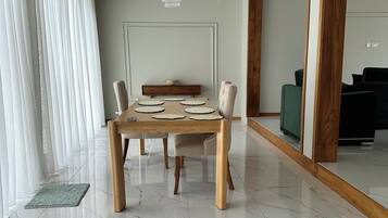 Een moderne eetruimte met een houten tafel, zes stoelen en een kroonluchter.