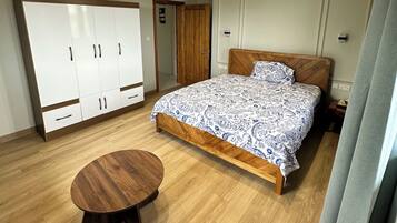 A bedroom with a bed, wardrobe, and a round wooden table.