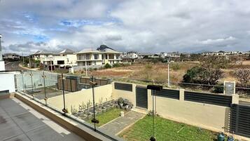 A residential area with houses, a paved courtyard, and a view of distant buildings.