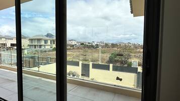 A room with large sliding glass doors leading to an outdoor area with a view of residential buildings and a clear sky.