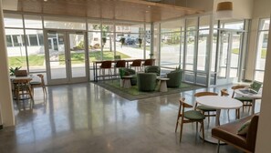 A spacious indoor area with large windows, seating arrangements, and a view of the outside. - Landing | Amazing 1BD in West Side (Grand Rapids)
