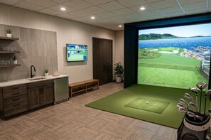 Cozinha moderna com TV integrada, espaço com tema de golfe e vista para o campo, e um banco de madeira.