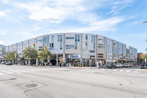 Un bâtiment moderne à la façade incurvée, avec une entrée bien visible et une enseigne « SPARITE MART » au rez-de-chaussée.