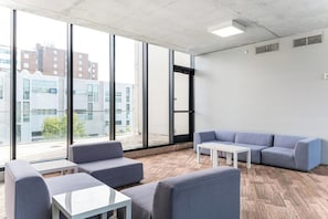 A modern office space with large windows, a grey sofa, a white table, and a patterned wall. - Landing | Beautiful 1BD in University Circle (Cleveland)