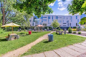 A courtyard with a picnic table, a trash bin, and a bench. - Landing | Stunning 1BD in University Circle (Cleveland)